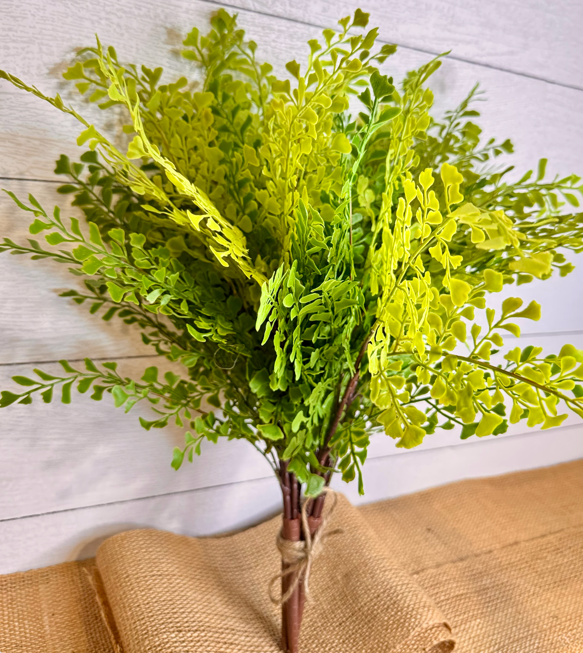 Artificial maidenhair fern bundle with lime-green fronds, brown stems, bundled with twine on burlap