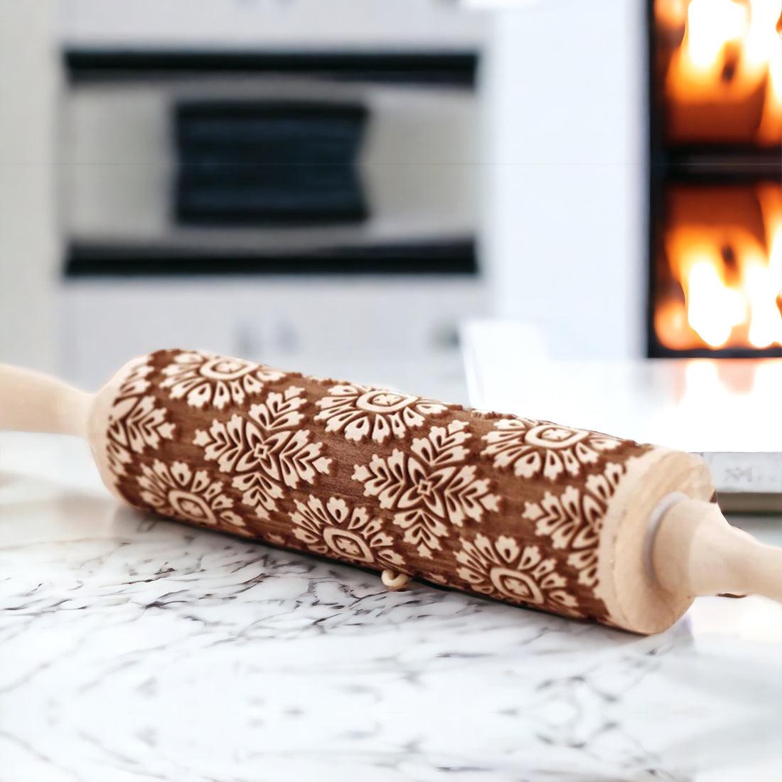 Embossed wood rolling pin with dark floral motif on a white marble surface