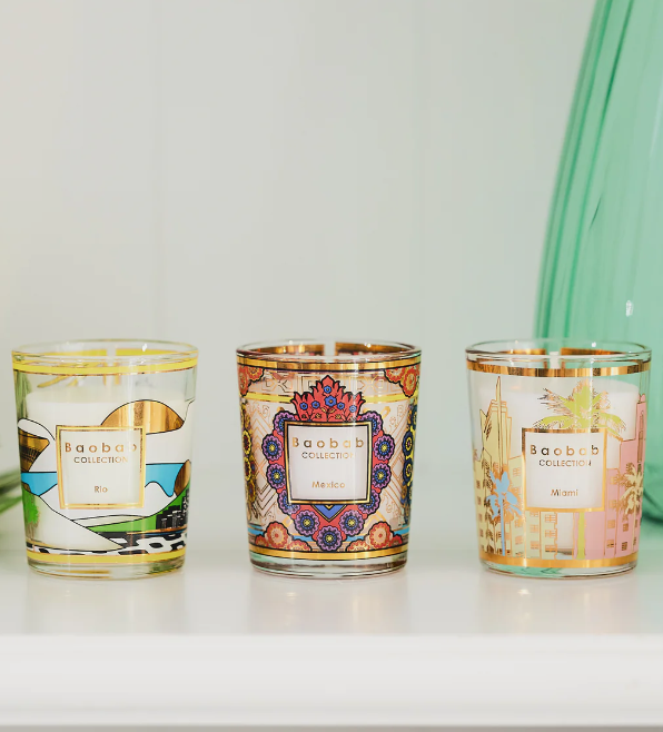 Three Baobab travel candles in clear glass jars with colorful patterned labels
