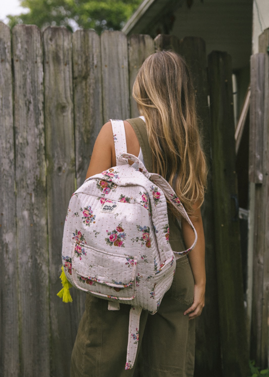 Light pink quilted floral mini backpack with adjustable straps and dangling yellow tassels