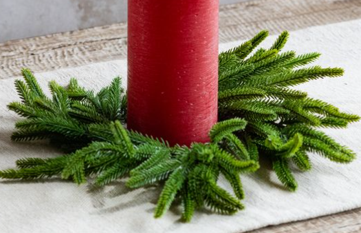 Pine candle ring with green branches arranged around a red pillar candle