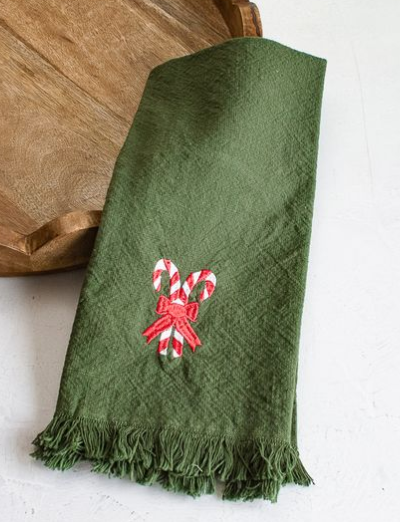 Green towel with fringed edges and an embroidered red-and-white candy cane bow