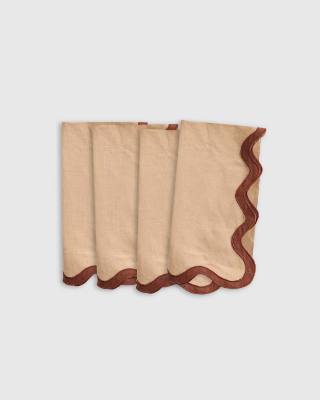Set of beige linen napkins with scalloped edge and dark brown trim, folded