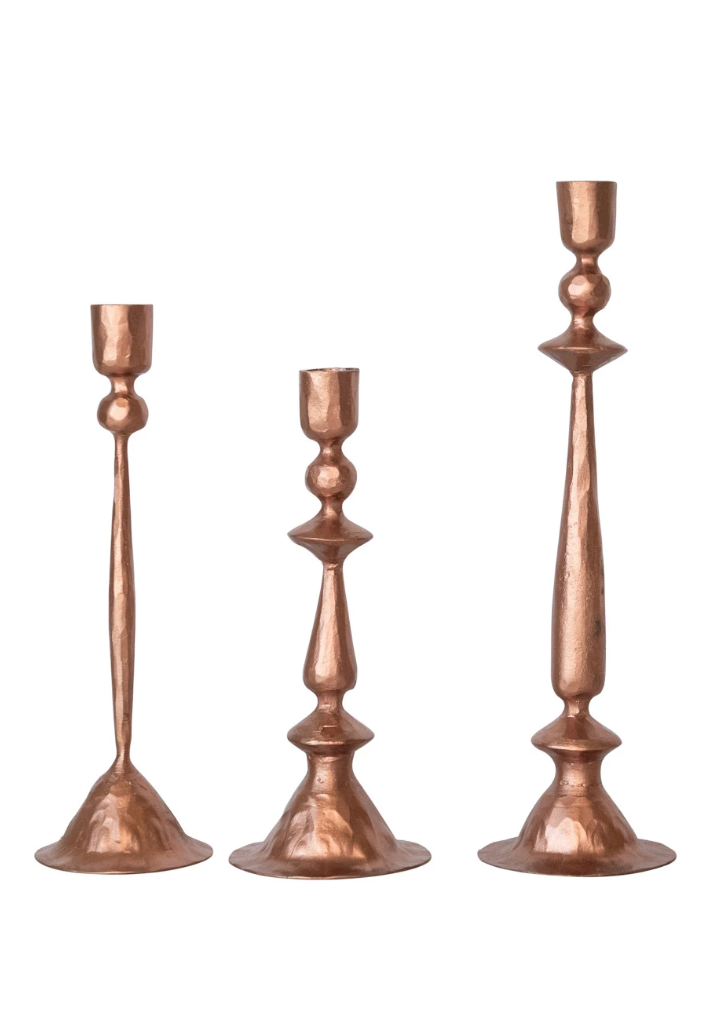 Set of three copper taper candleholders with flared cups and weighted bases.