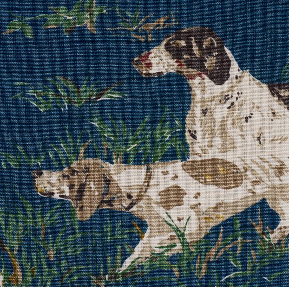 Close-up of navy pillow cover print featuring speckled dog in green plants.