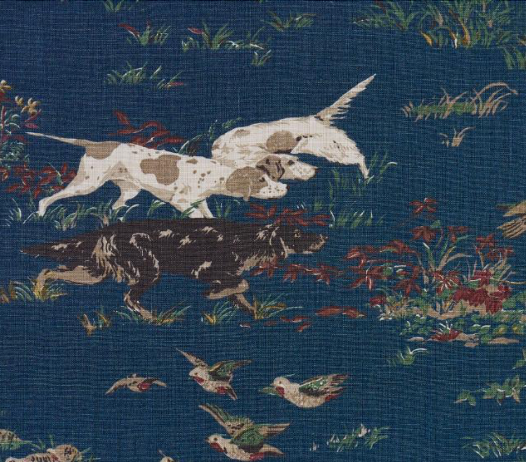 Close-up of navy pillow cover print with white dog and scattered birds in grass.