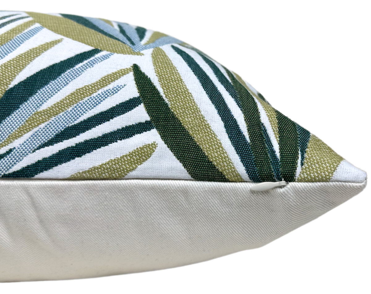 Throw pillow cover edge and corner seam with tropical leaf print in teal, green, and cream.