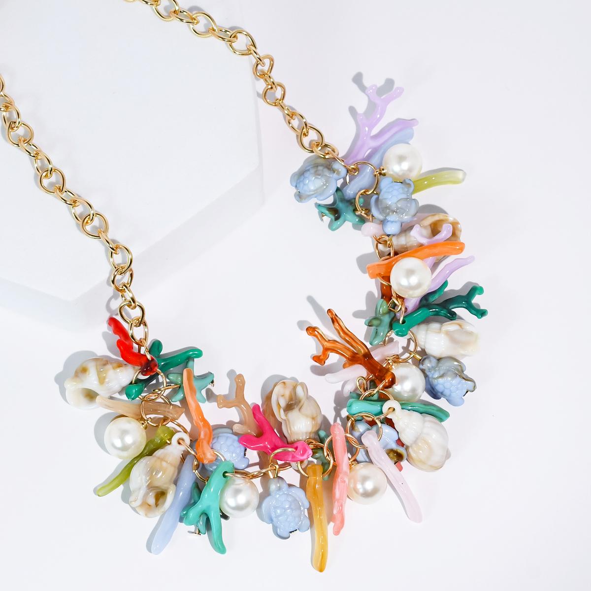 Sea charm necklace with gold chain and colorful coral, pearls, and seashell charms