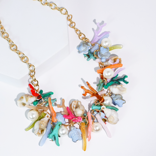 Sea charm necklace with gold chain and colorful coral, pearls, and seashell charms