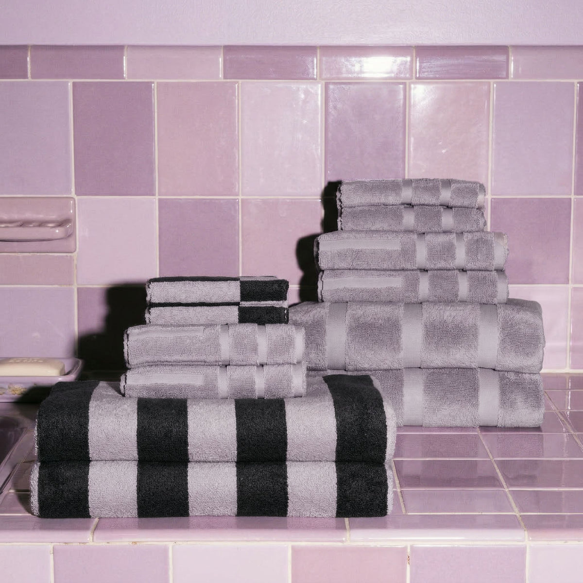 Folded lilac and charcoal towels stacked together, with black-and-white striped towel
