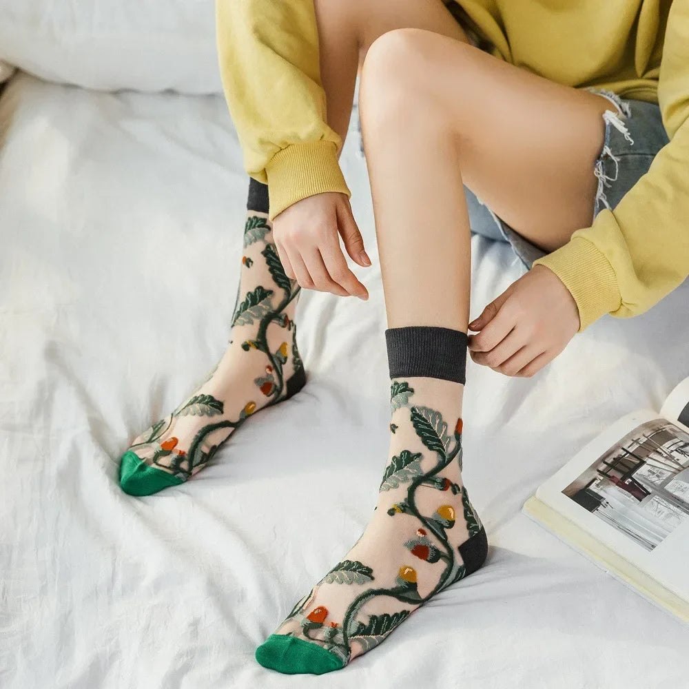 Sheer crew socks worn on model: grey botanical pattern with orange berries and green toe
