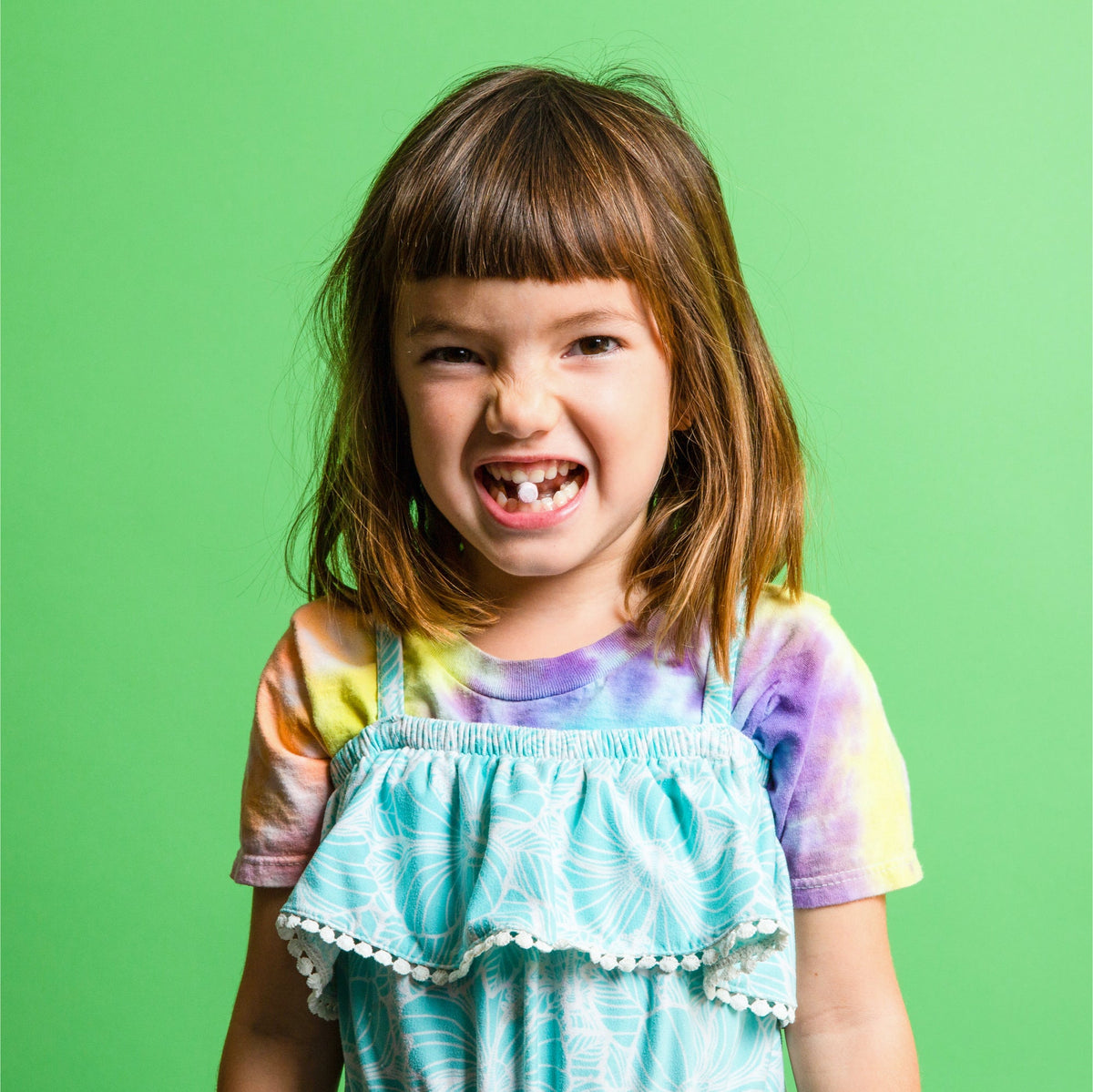 Child smiling with a toothpaste tablet visible in their mouth