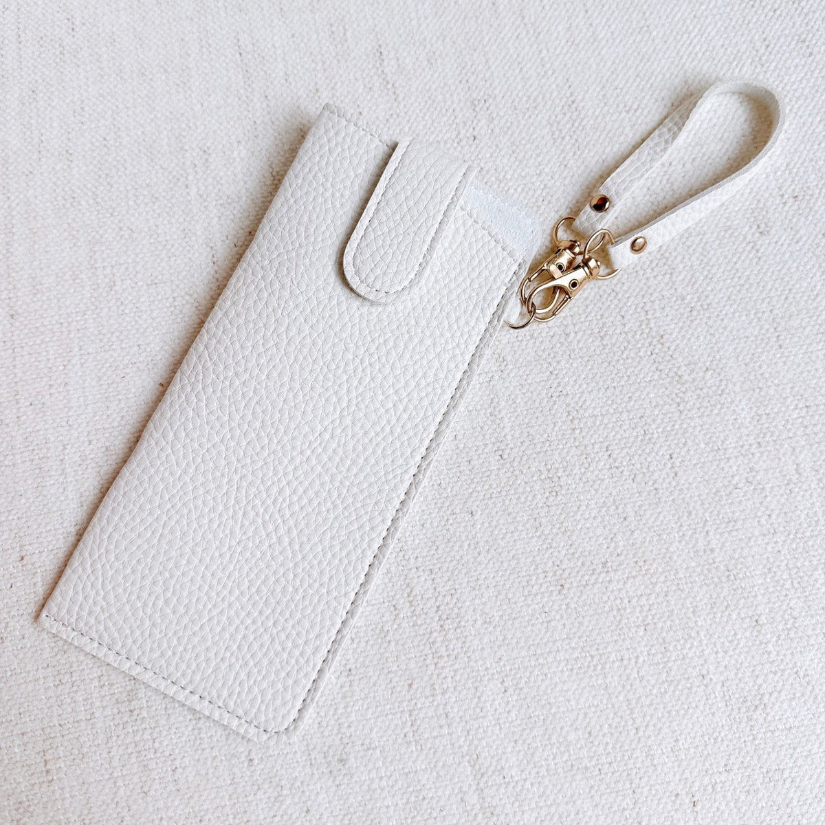 White bag charm glass case with wrist strap and gold-tone clasp