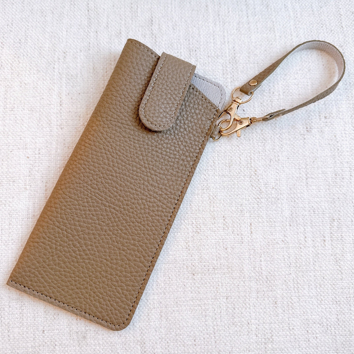 Tan bag charm glass case with wrist strap and gold-tone clasp