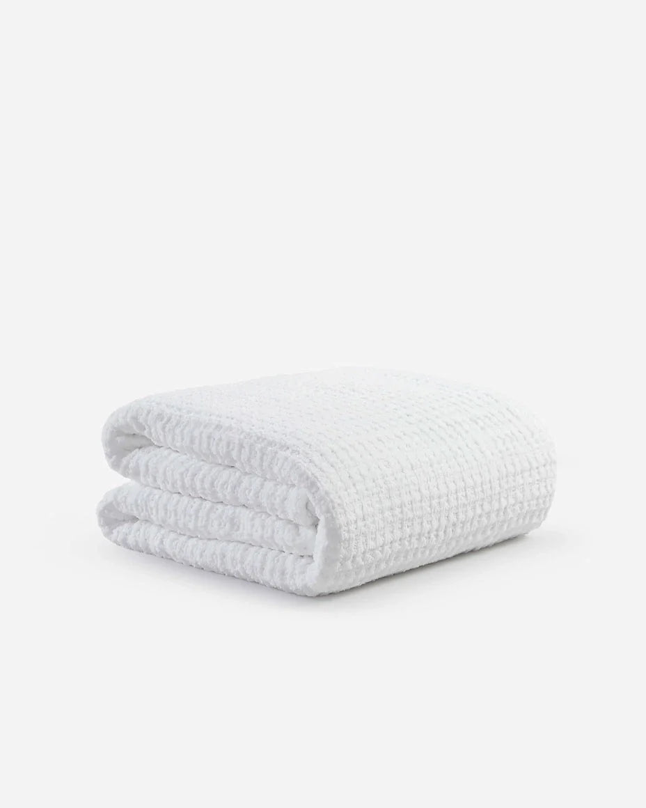 Folded white waffle comforter, plush textured surface and stacked layers