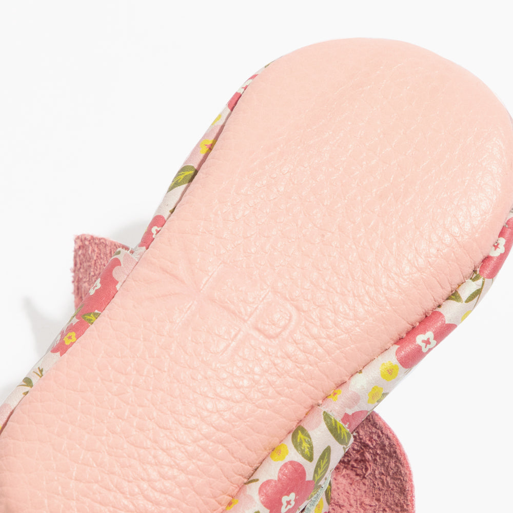 Close-up of baby floral slip-on shoe with knotted pink bow and textured leather
