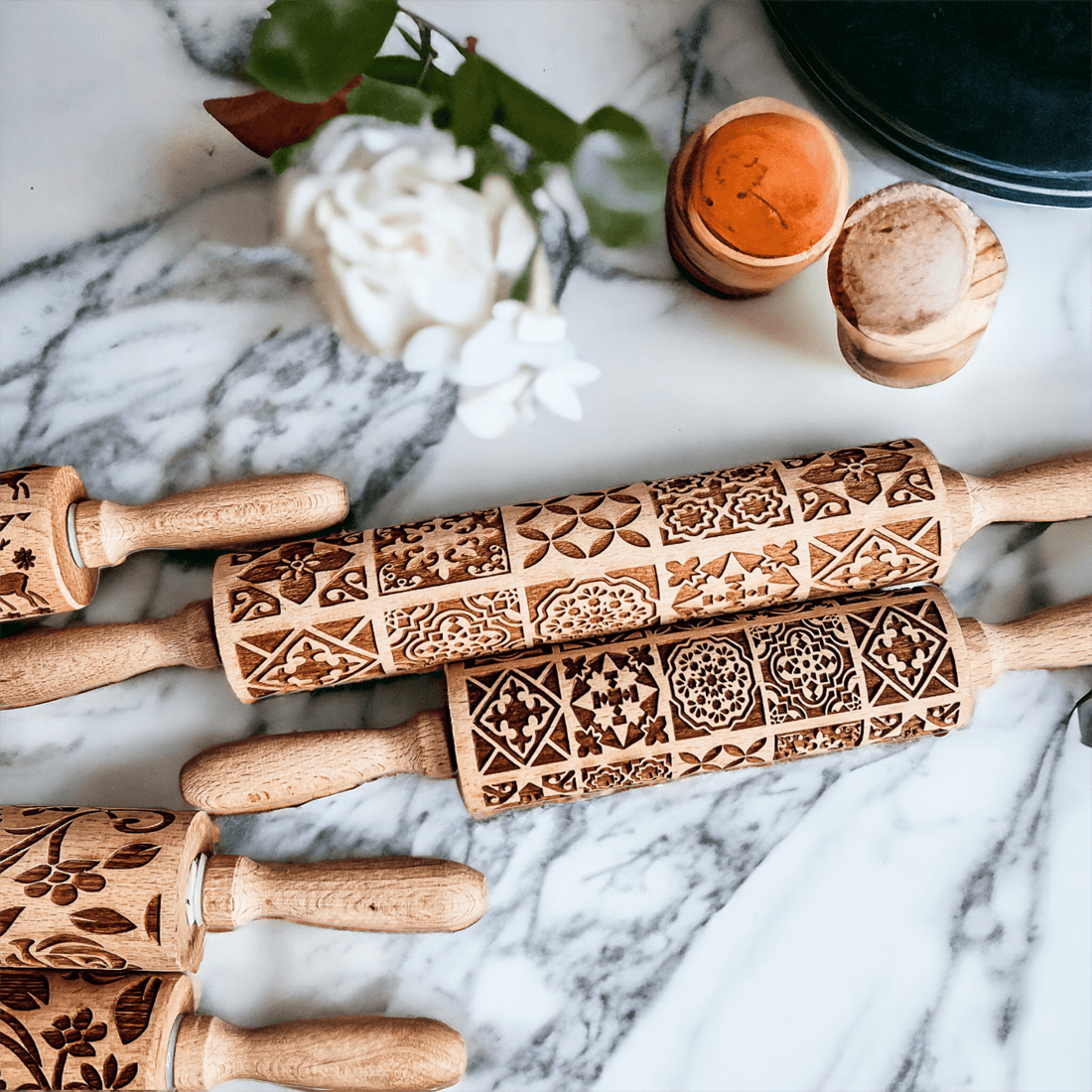 Decorative rolling pin set on marble with wood handles and brown patterned sleeves