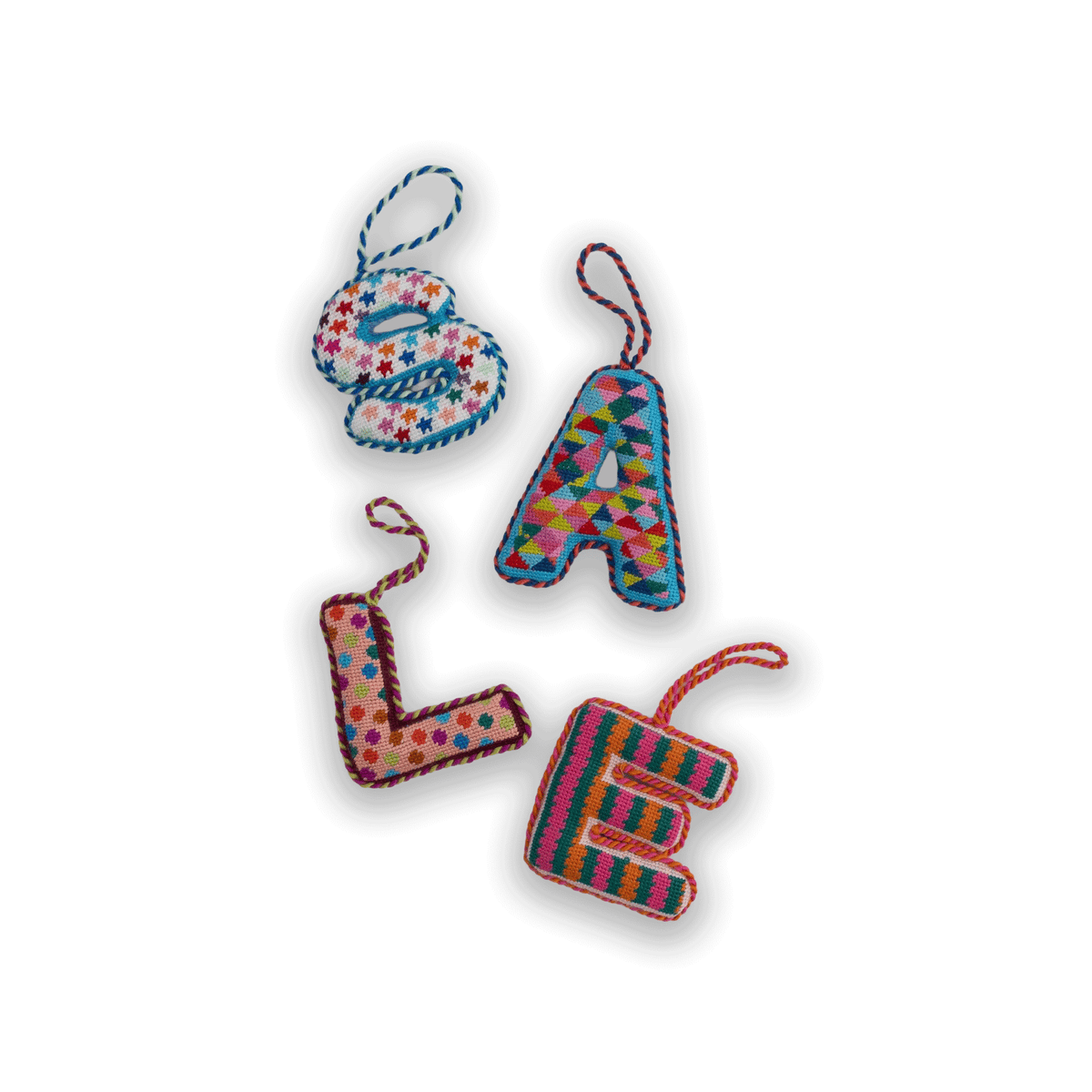Needlepoint monogram ornament with multicolor stitched letters and hanging cords.