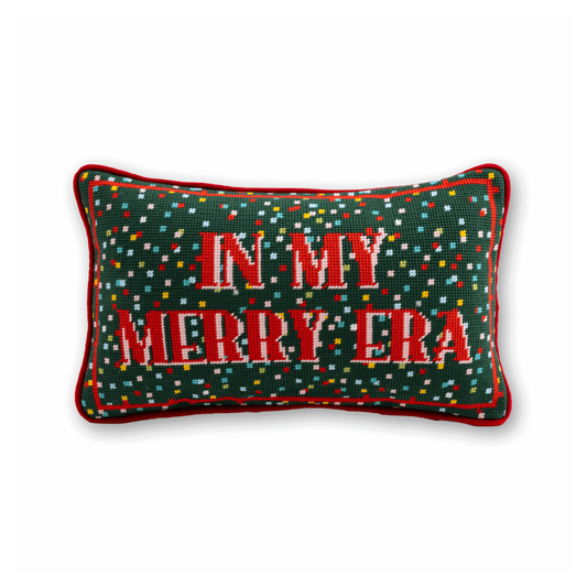Green needlepoint pillow with red trim and IN MY MERRY ERA stitched text