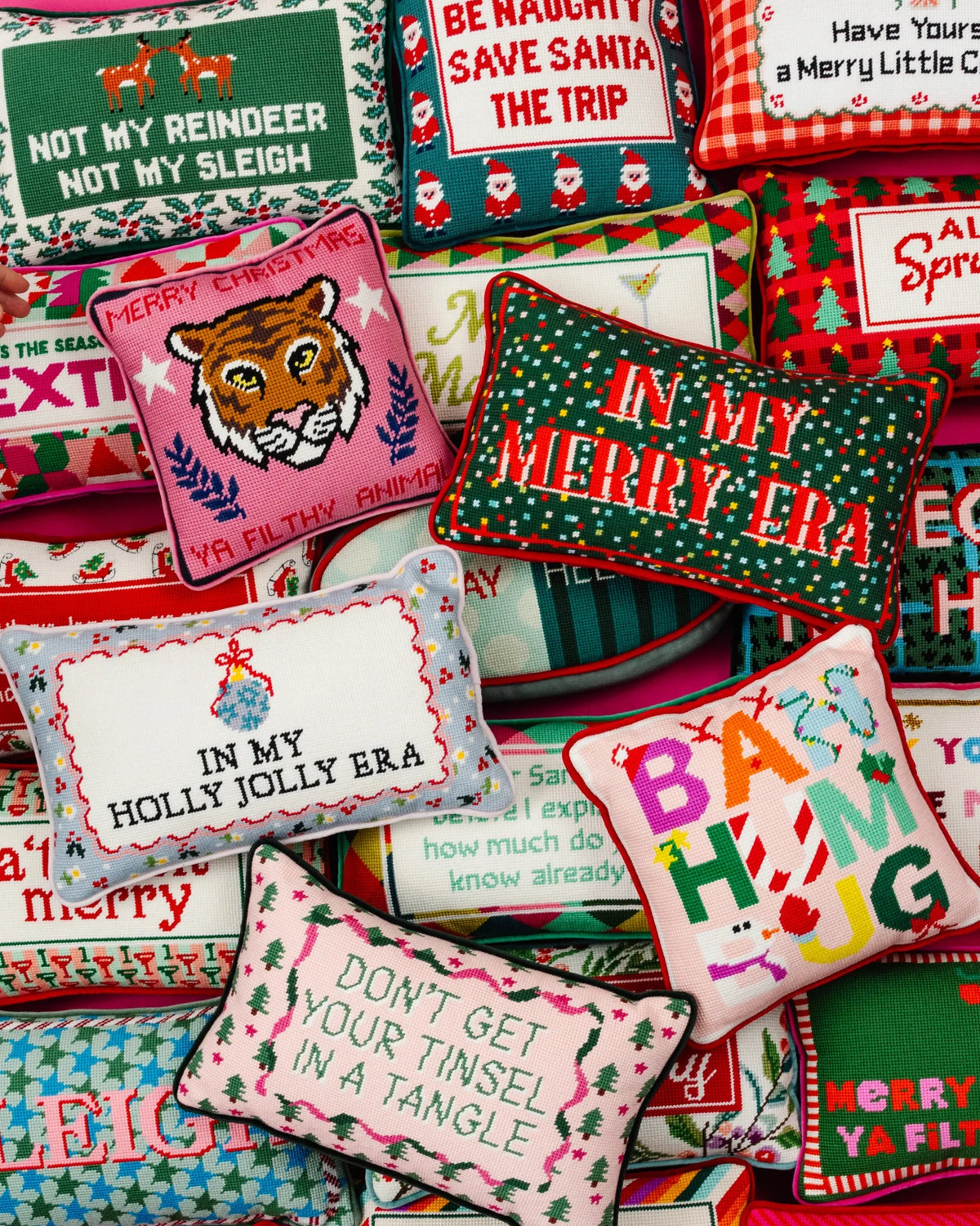 Assorted needlepoint holiday pillows with festive square designs and lettering