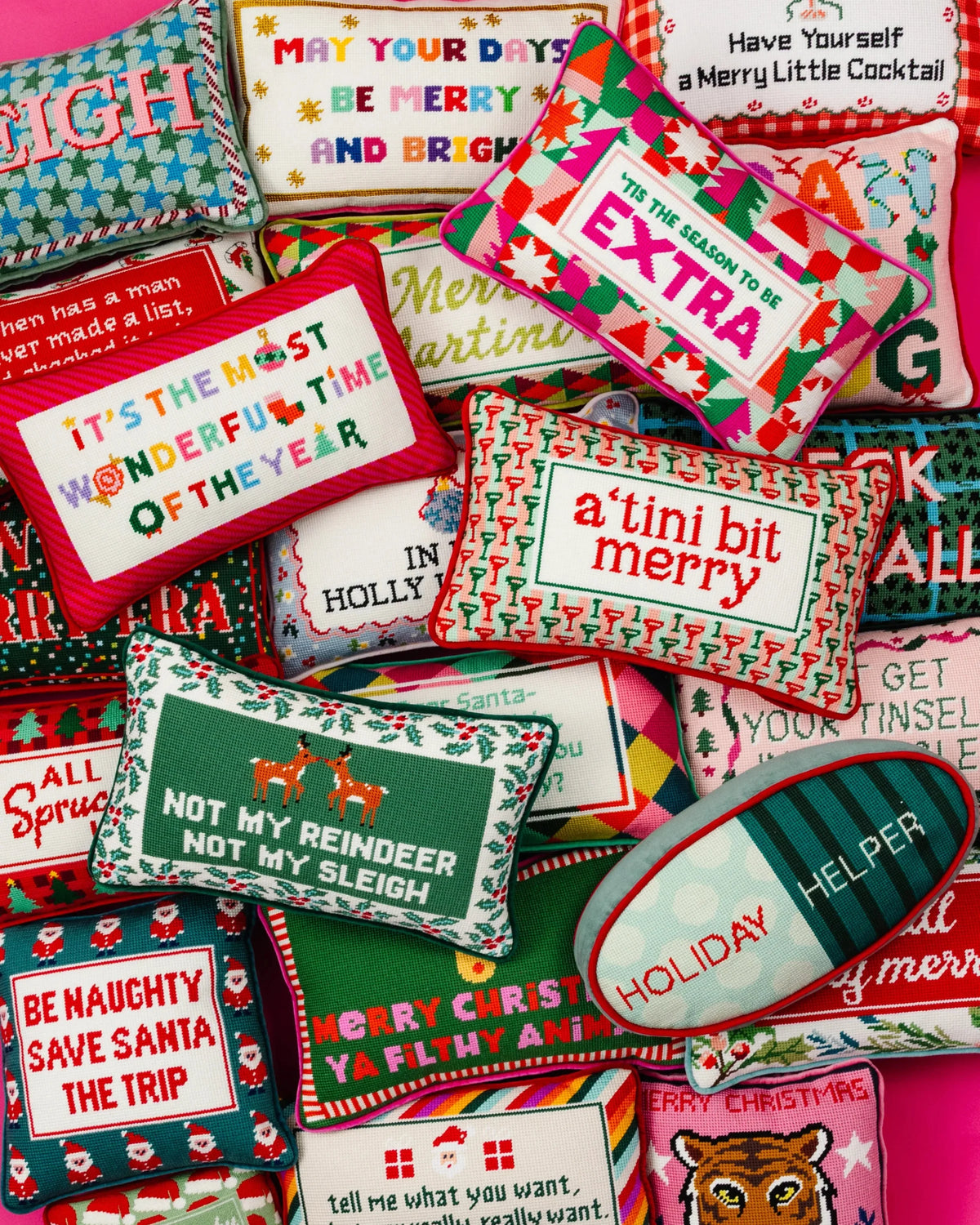 Assorted needlepoint Christmas pillows with colorful text, including 'TIS THE SEASON TO BE EXTRA'.