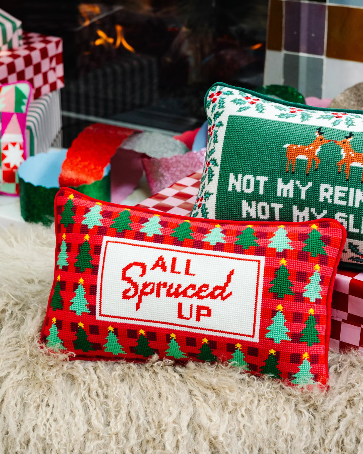 Christmas needlepoint pillow with 'All Spruced Up' sign, red border, green tree motifs