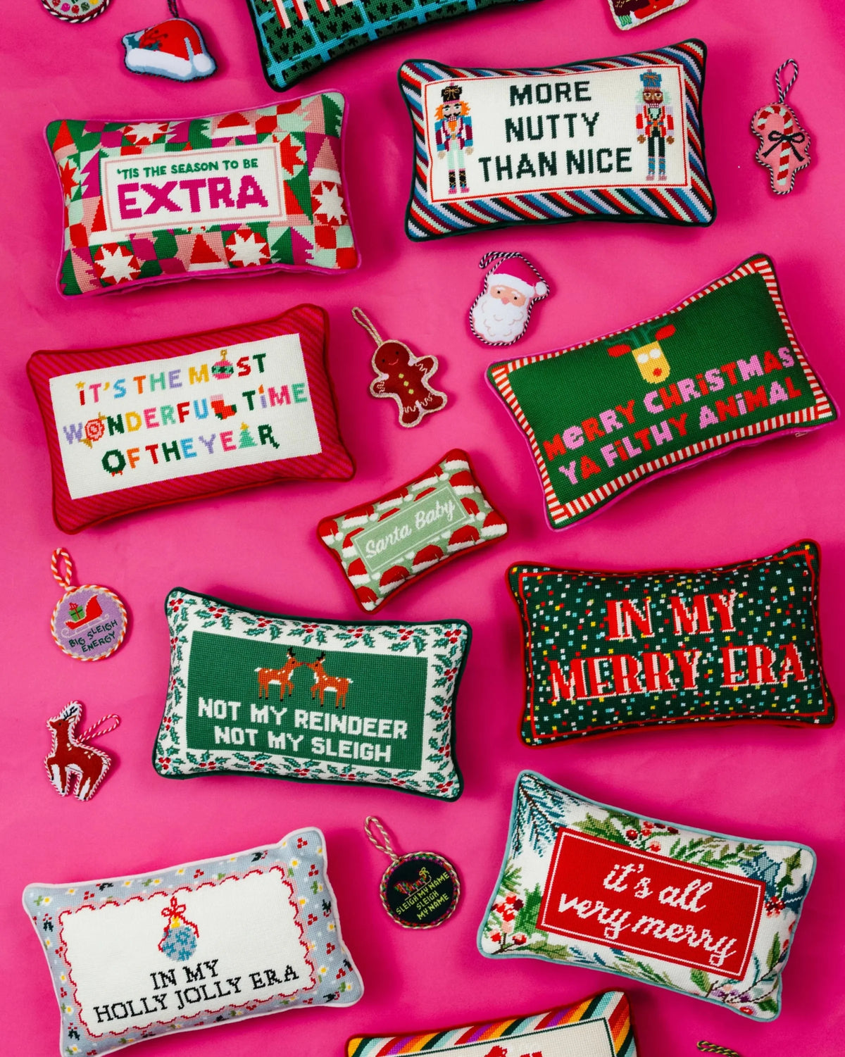 Mini needlepoint pillow with Santa Baby text in red and green on colorful flat lay