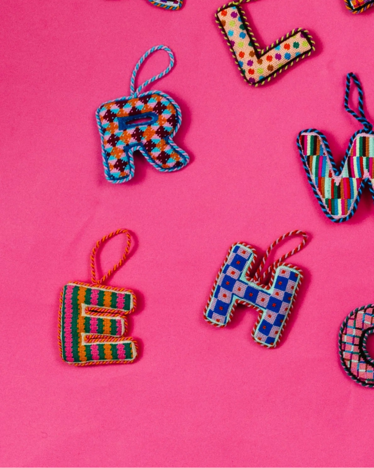Needlepoint monogram letter E ornament with blue and orange geometric stitch pattern, loop top.