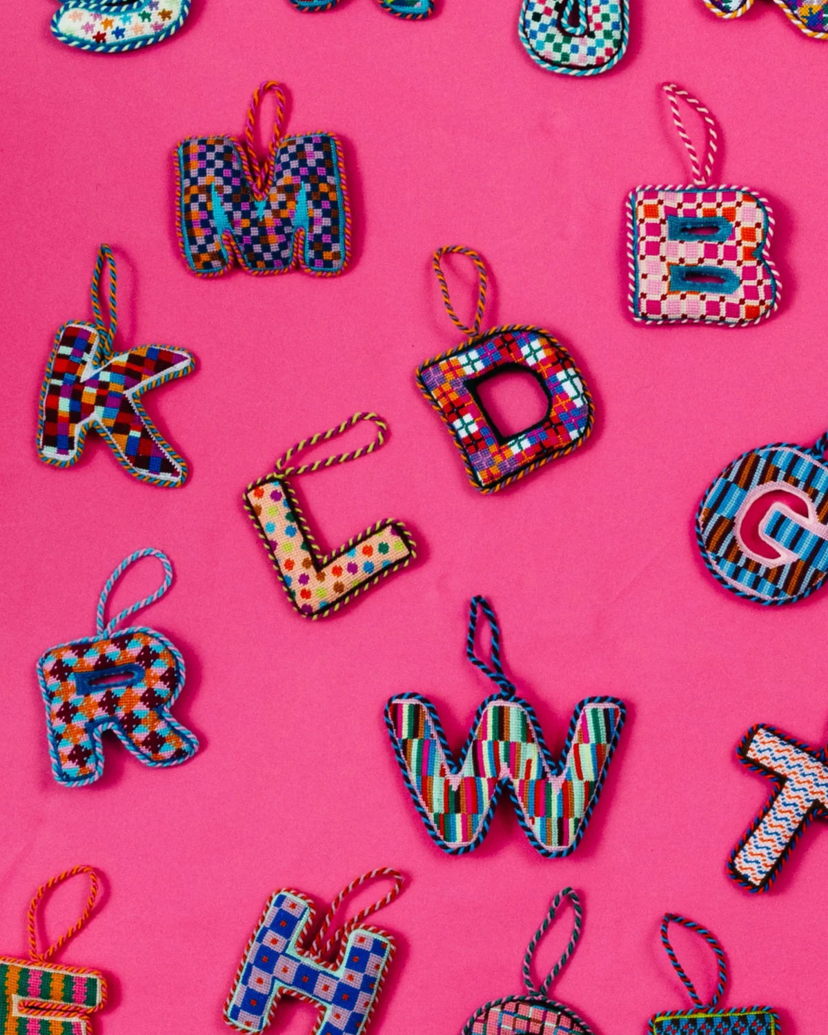 Needlepoint monogram letter ornaments with multicolor plaid fabric and hanging loops
