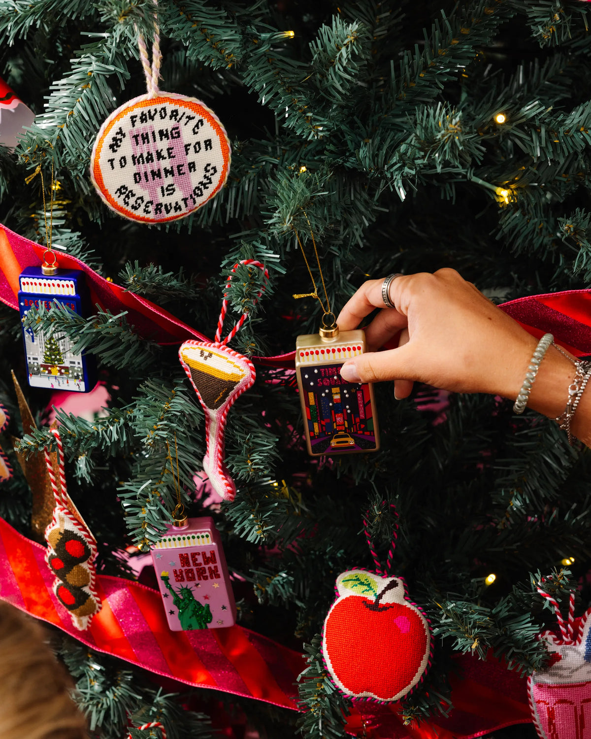 Red apple needlepoint ornament hanging on tree, stitched details, braided loop
