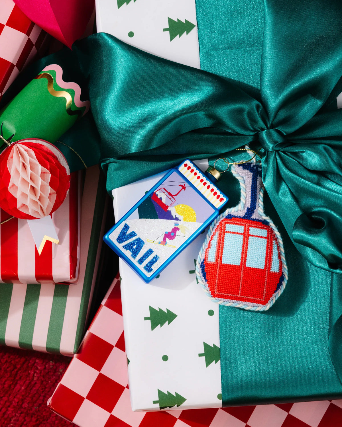 VAIL matchbook ornament hanging on wrapped gift with festive patterns.