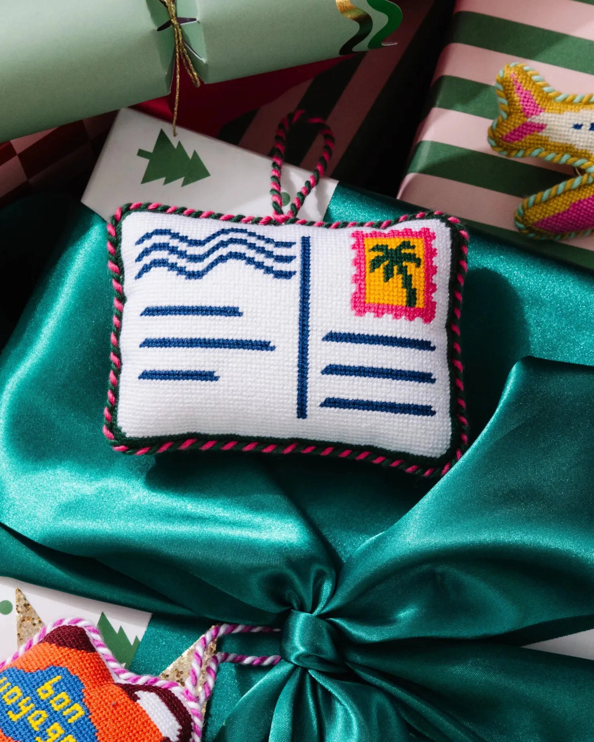 Needlepoint postcard ornament on red and teal gift, red green stitched edge