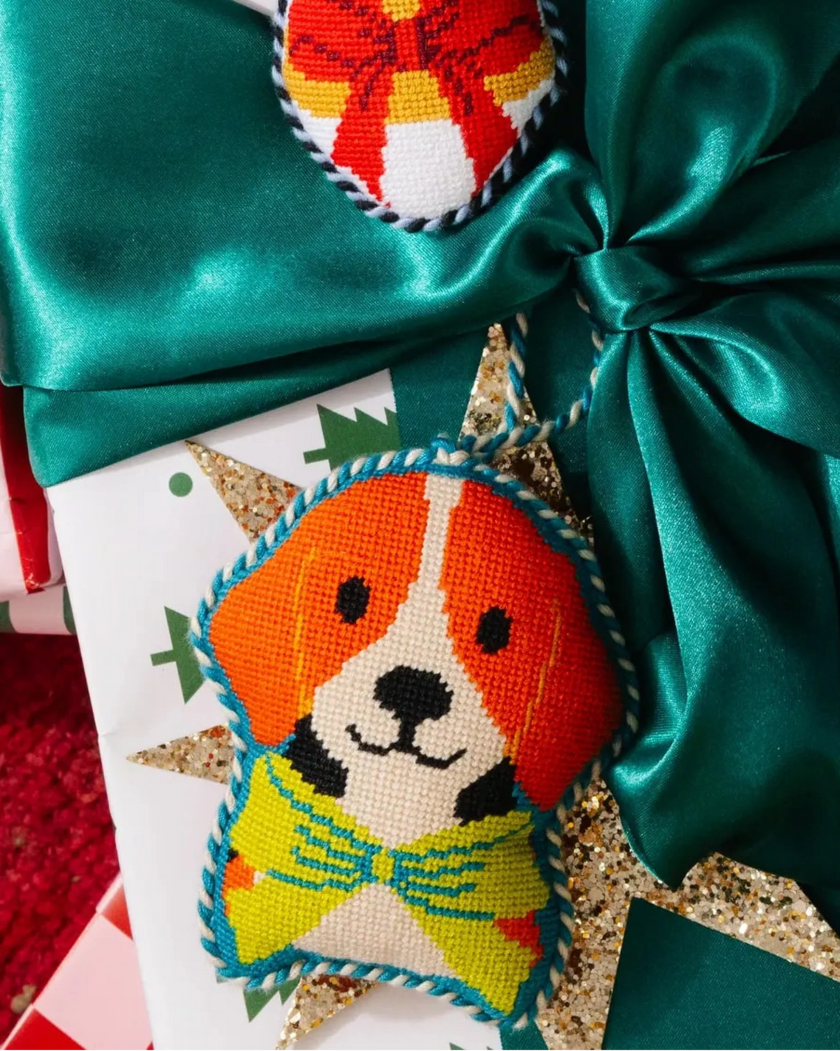 Beagle needlepoint ornament with orange dog face and green striped scarf, hanging twine