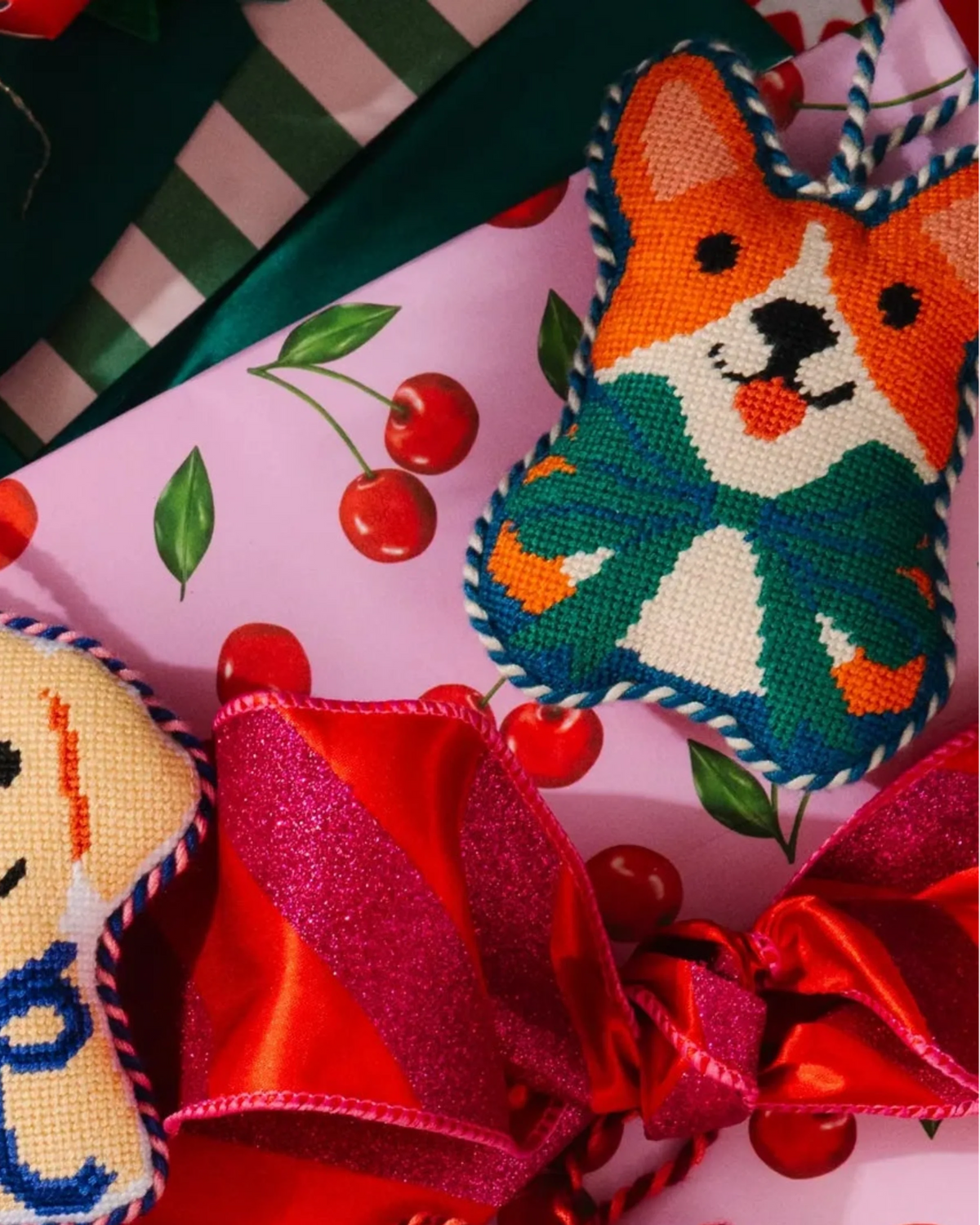 Corgi needlepoint ornament with orange face, teal collar, and striped hanging cord