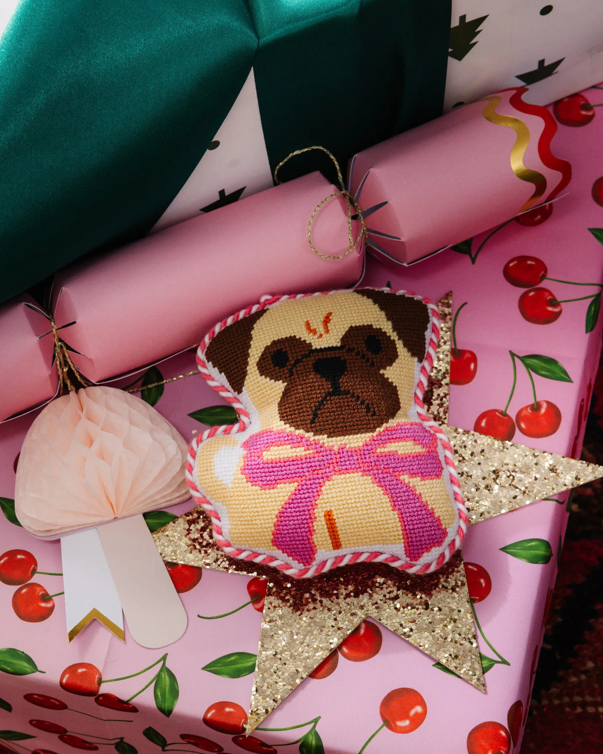 Needlepoint pug ornament tucked in gift wrap, tan and brown dog face