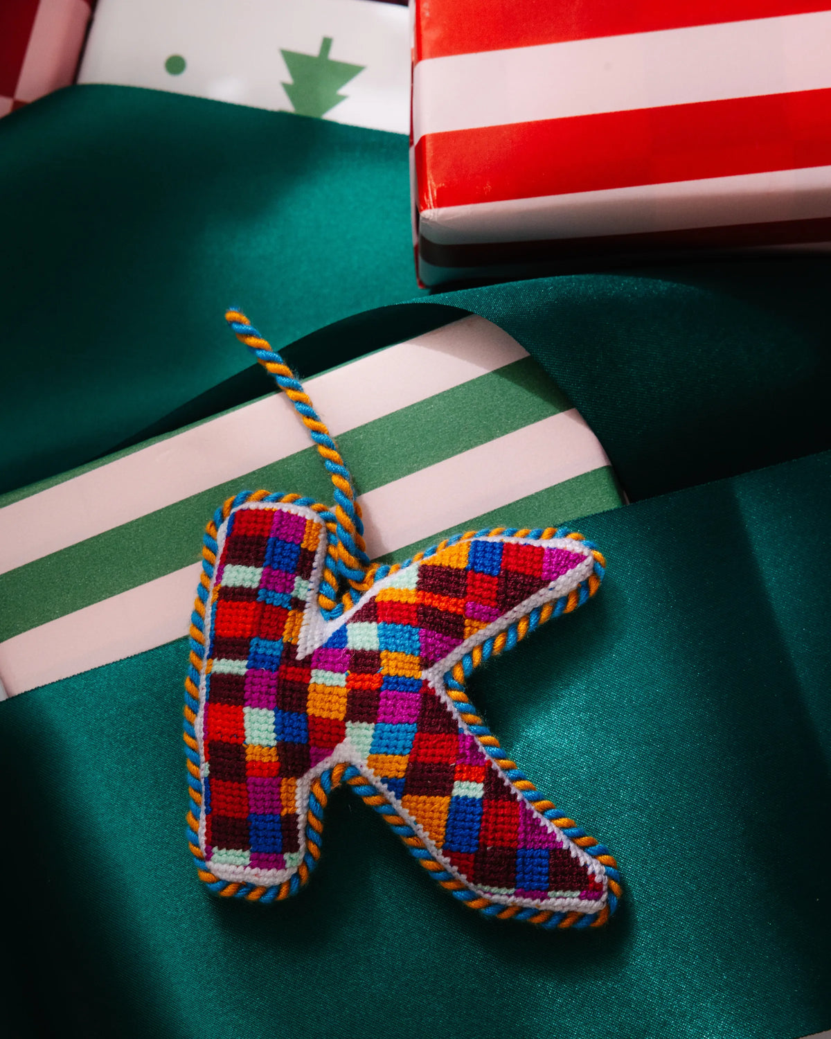 Needlepoint monogram ornament K with multicolor patchwork stitches and rope hanger