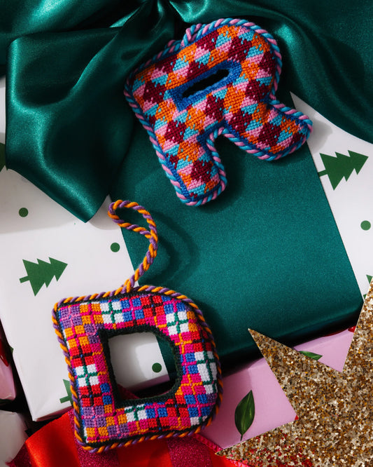 Needlepoint monogram letter D ornament in multicolor plaid stitches with braided hanging cord