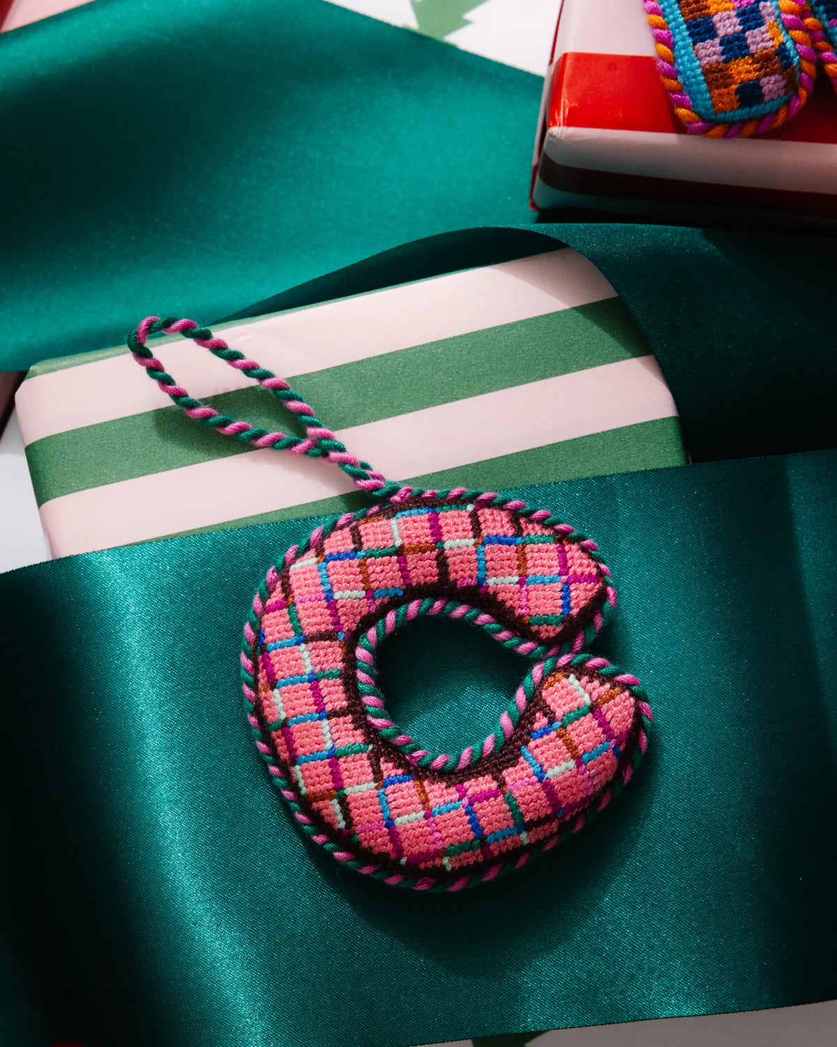 Needlepoint letter C ornament in pink, teal, and blue plaid with braided hanging cord.