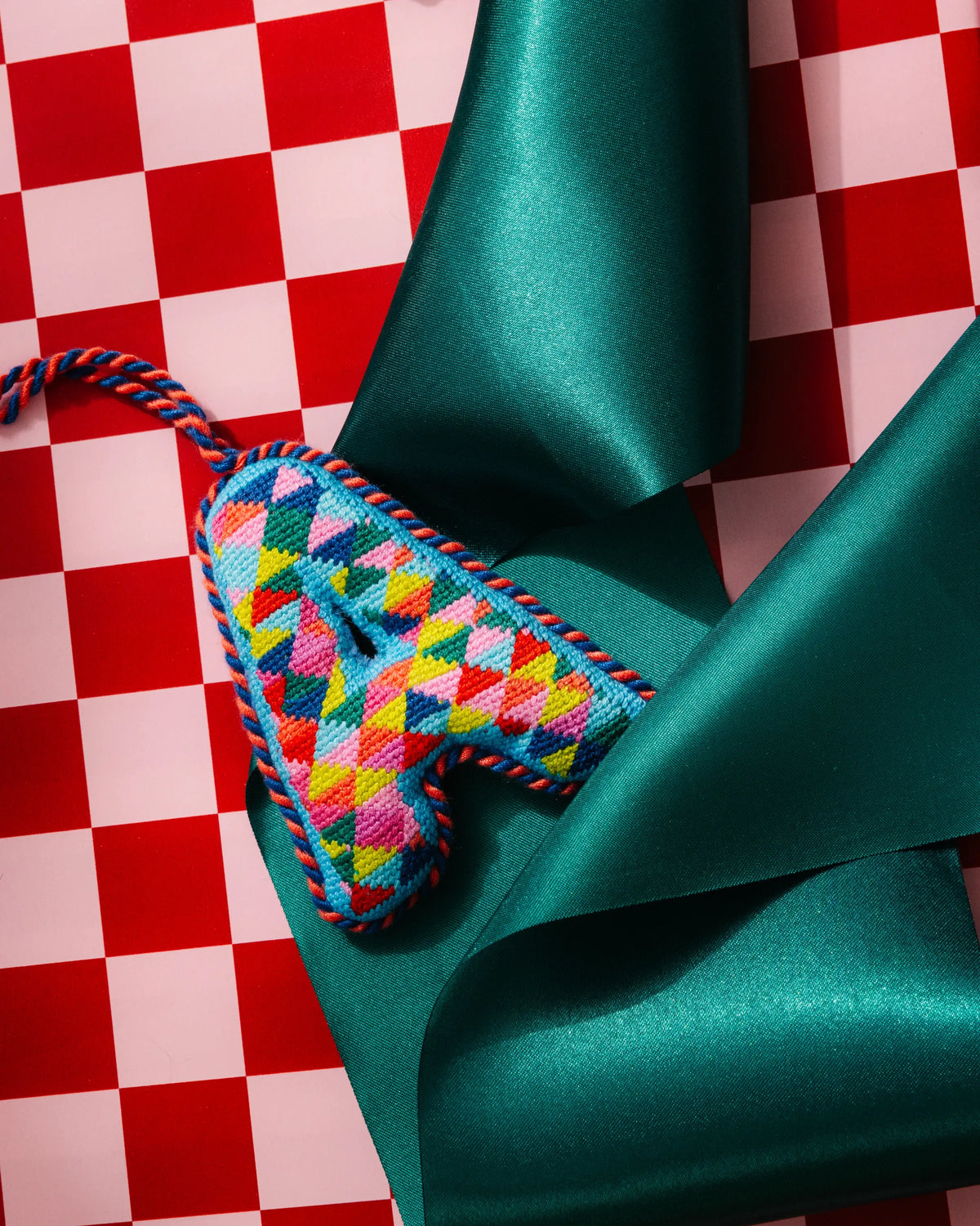 Needlepoint letter A ornament detail, multicolor cross-stitch with braided hanger