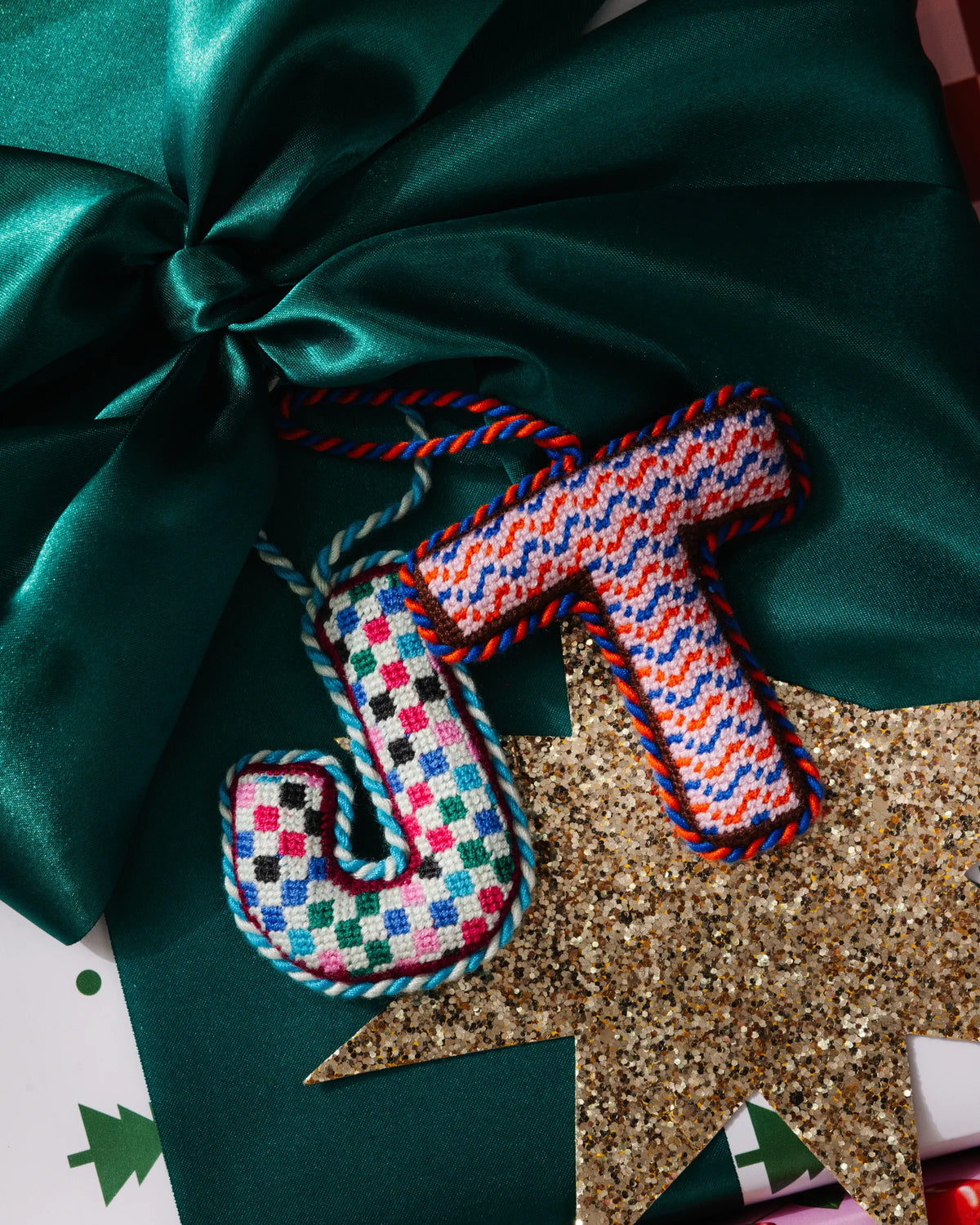 Needlepoint T ornament with multicolor zigzag and diamond stitches, blue-red border
