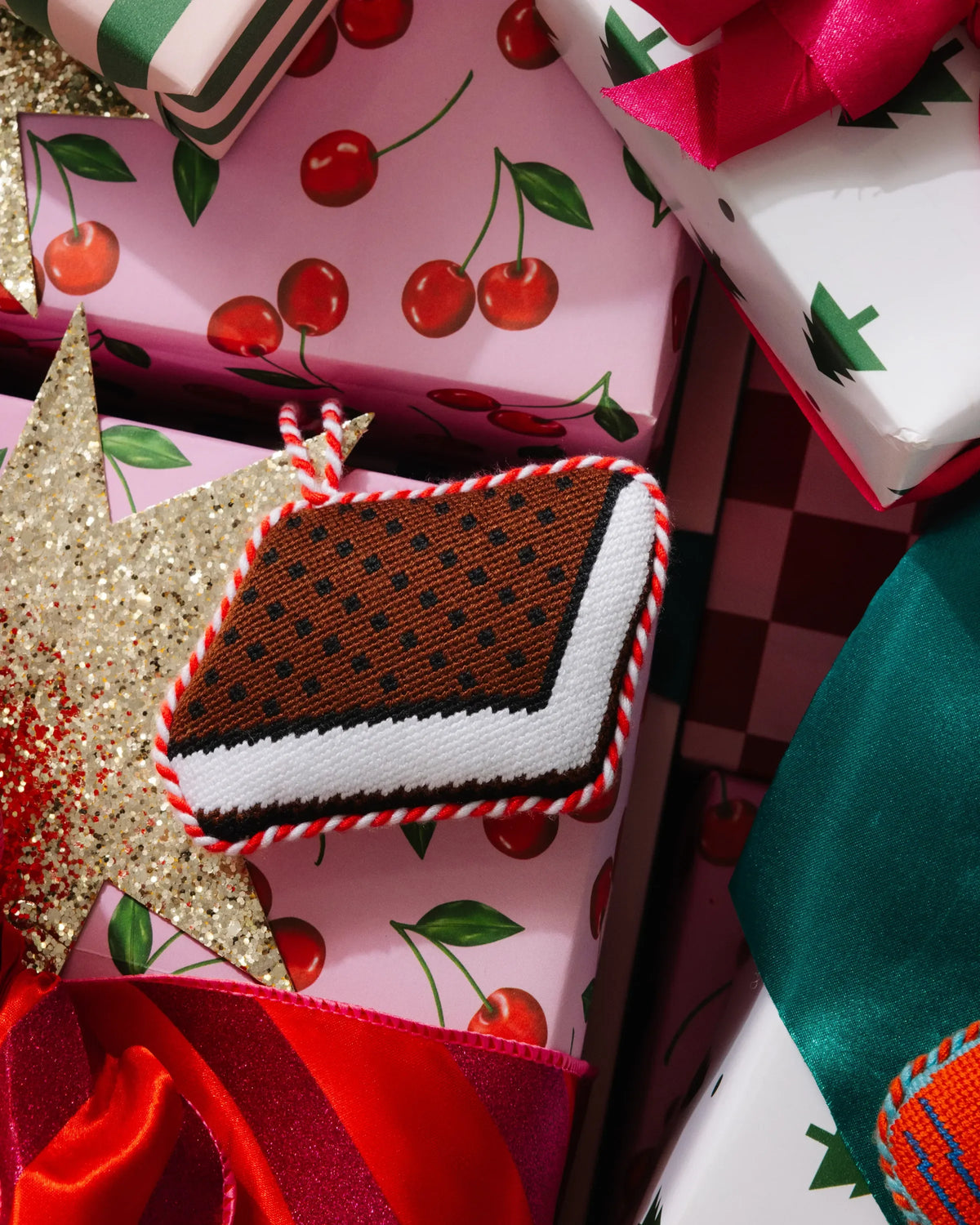 Needlepoint ice cream sandwich ornament, brown and white layers with red-and-white braided edge
