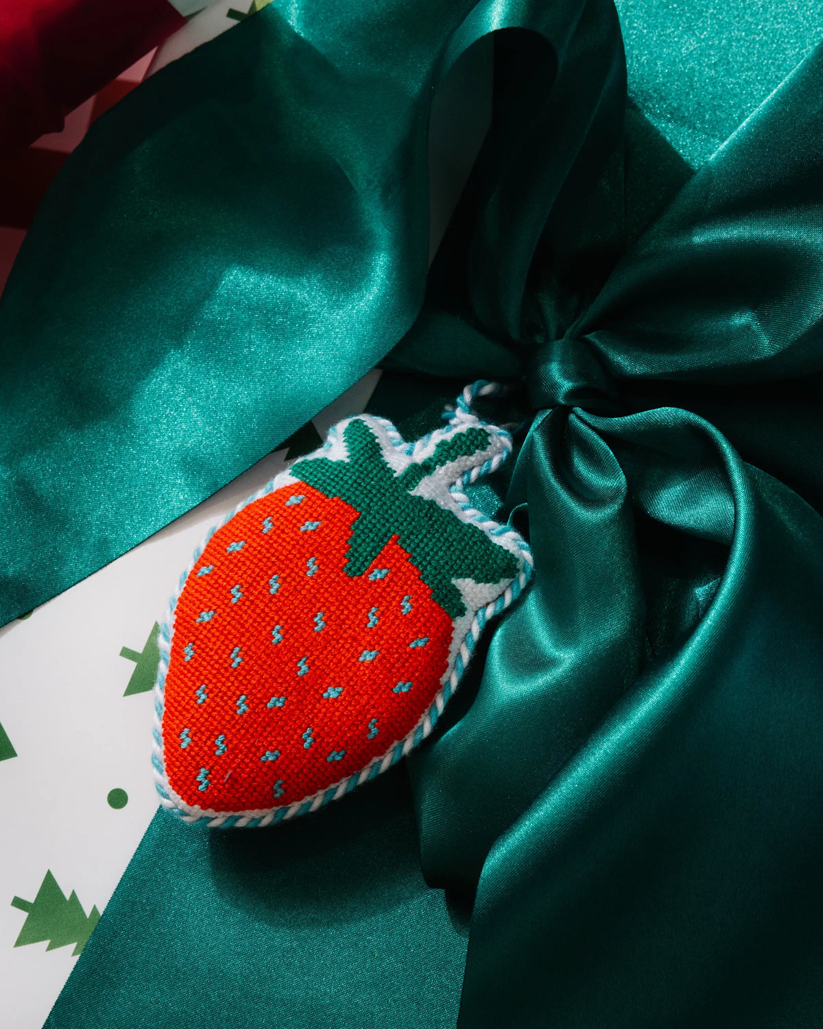 Needlepoint strawberry ornament with hanging loop, tied with teal satin ribbon