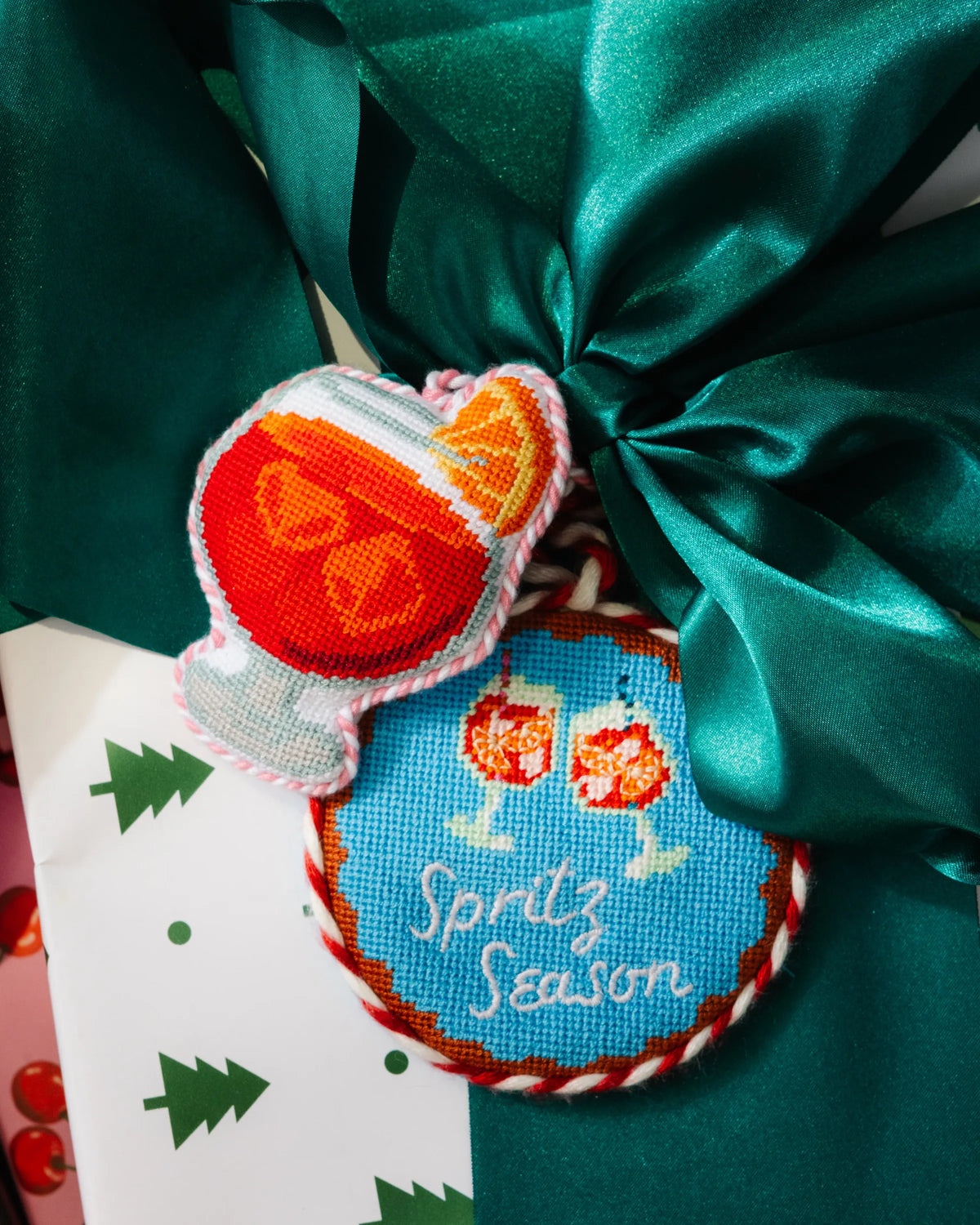 Needlepoint cocktail icon ornaments with green ribbon, red and blue stitched designs