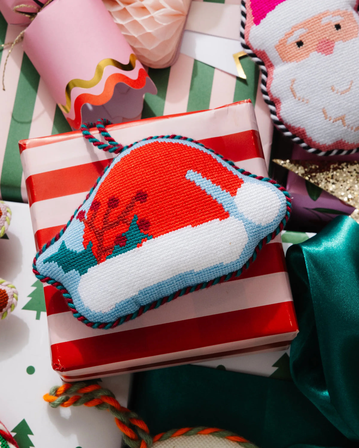 Needlepoint Santa hat icon ornament with braided cord loop, red brim and white trim