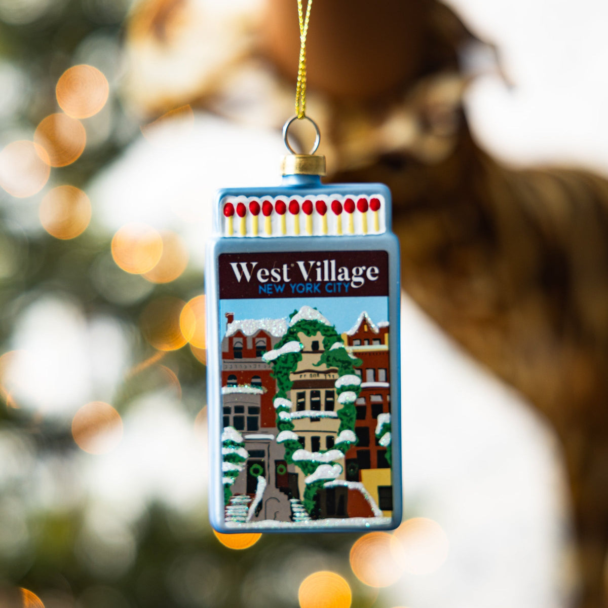 Blue matchbook ornament with West Village New York City scene, hanging on gold cord