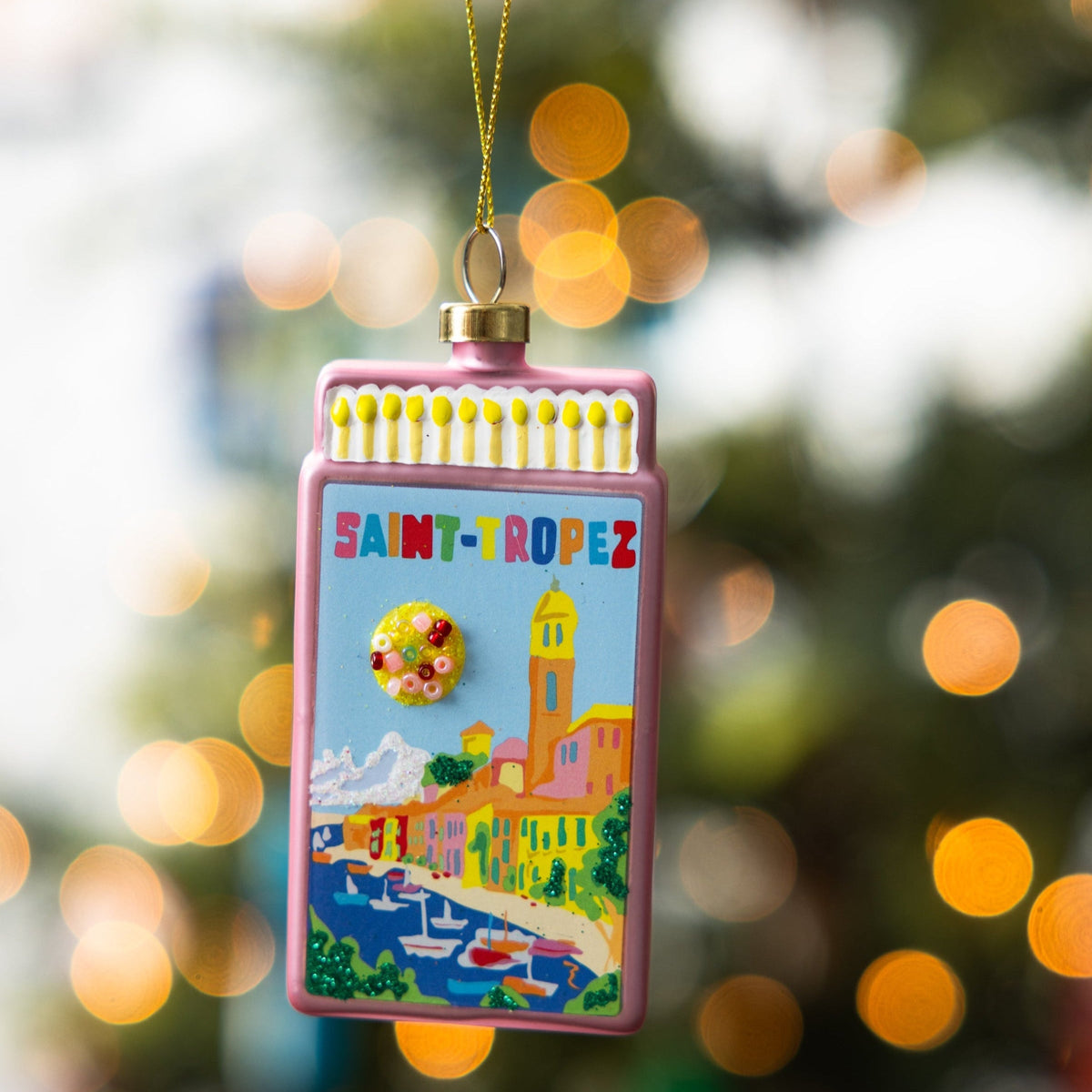 Pink matchbook ornament hanging with gold cord and St. Tropez scene