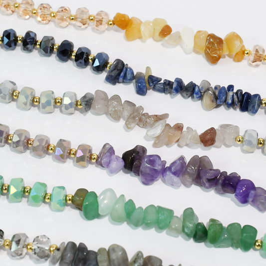 Assorted beaded quartz necklaces with gold-tone accents in pink, navy, purple, and green.