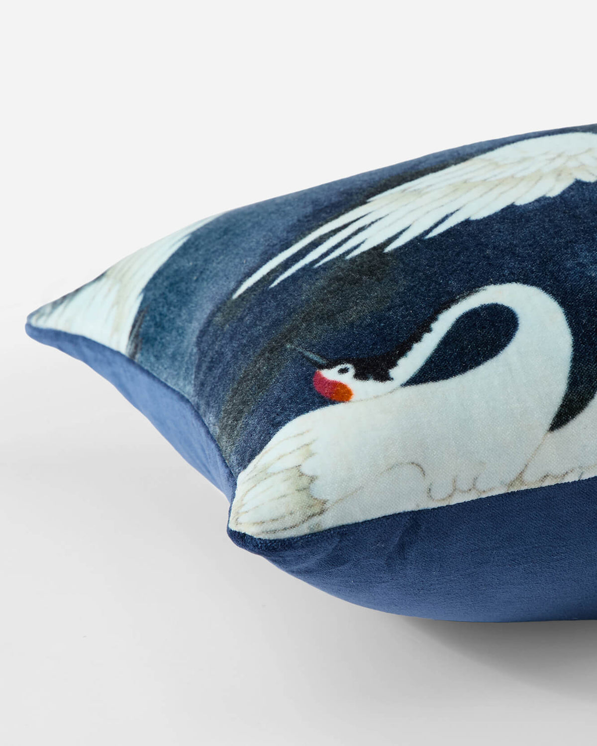 Close-up of dark blue small lumbar pillow with white crane face and red beak.