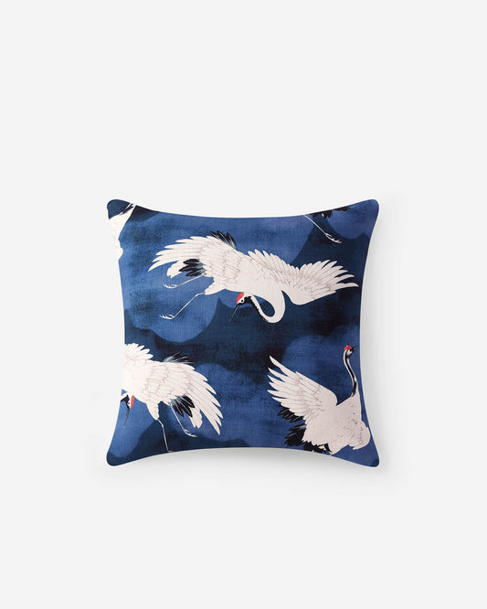 Blue decorative throw pillow with white crane bird pattern and dark accents