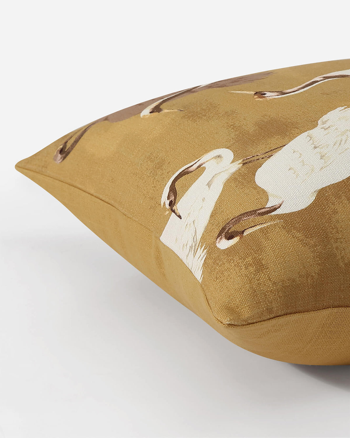 Gold throw pillow featuring close-up crane motifs in white and brown